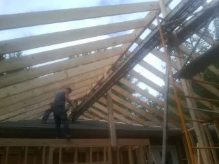 Rafters going up over a new addition with a worker on the wall in Hendersonville