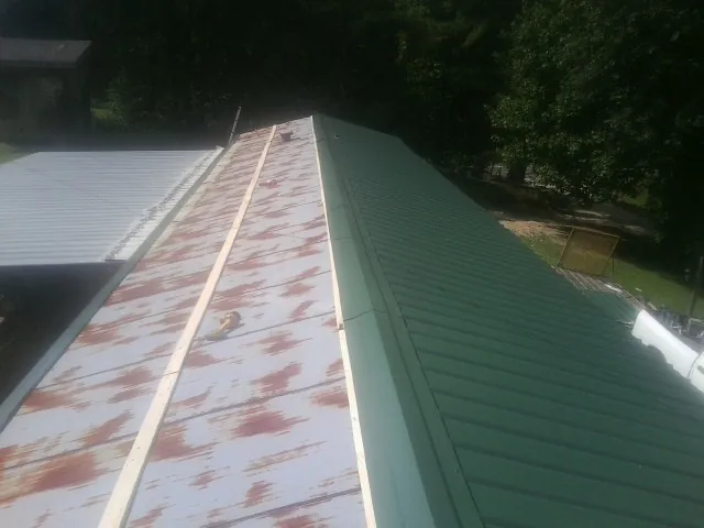 Old rusted panels beside newly installed green metal roofing — Wind Damage Roof Repair by Roofing Brothers in Hendersonville