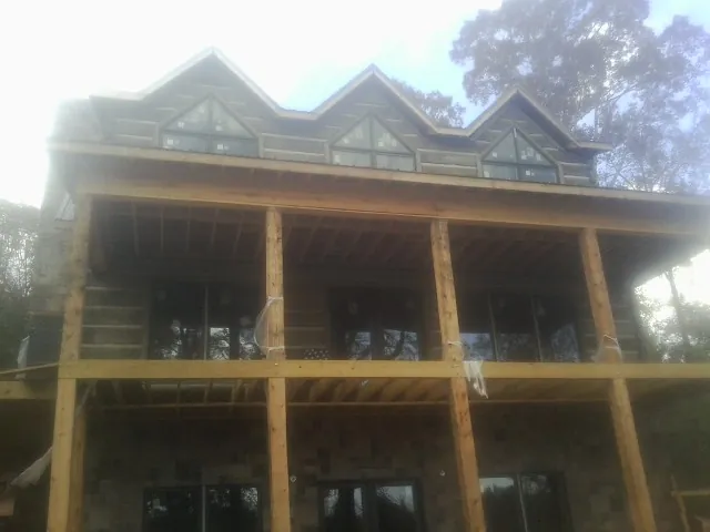 Dormers and porch framing on a large log home under construction — Roof Coating work by our crew in Hendersonville